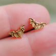 Load image into Gallery viewer, Golden bronze little bat studs between 2 fingers, by Studio Blue on Etsy