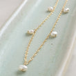Load image into Gallery viewer, White Baroque pearl drops on delicate 14k gold fill chain, shown on a light green background, by Studio Blue on Etsy