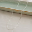 Load image into Gallery viewer, Dainty paperclip link chain necklace shown in Sterling silver, shown draped on a light green oblong ceramic dish and beige background. By Studio Blue on Etsy