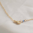 Load image into Gallery viewer, 14k Gold lobster clasp on cable chain finished with a blue bead on beige background by Studio Blue on Etsy