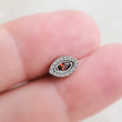 Load image into Gallery viewer, Titanium Evil Eye earring stud with pavé set clear CZ's around a red, marquise shaped CZ in the center, held between 2 fingers By Studio Blue on Etsy