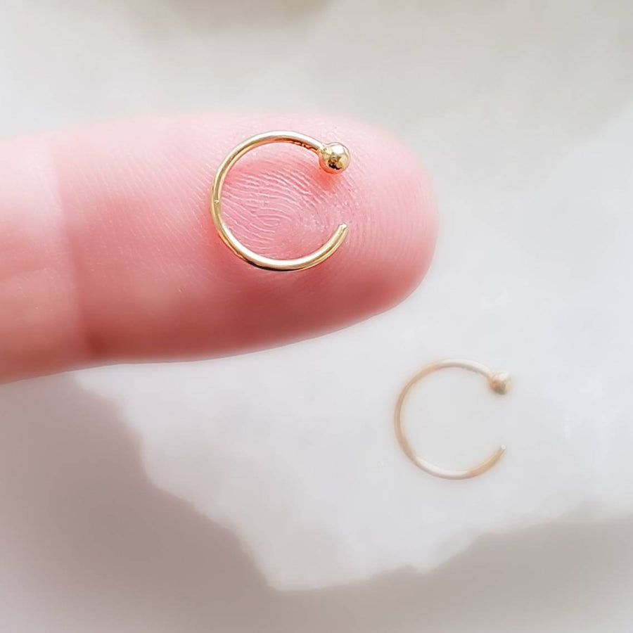 Yellow gold open hoops with 2mm ball beads one on index finger on white background