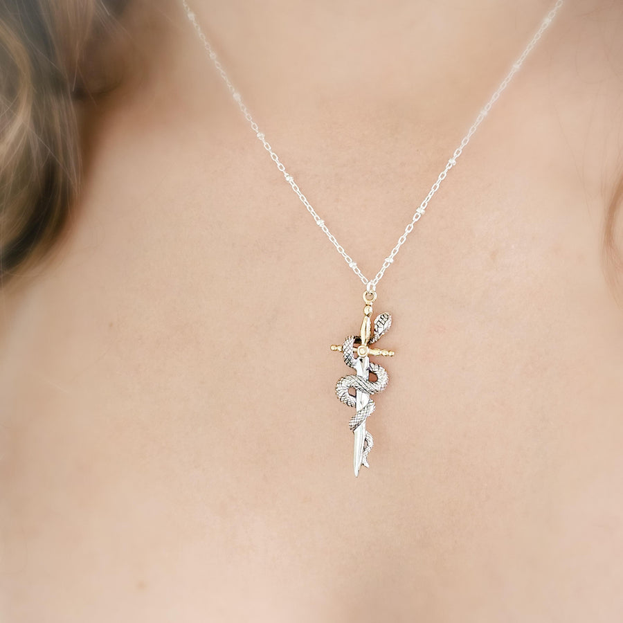 Model wearing the Snake & Dagger Necklace without birthstone accent, displaying the pendant’s balanced design and refined edge against a simple neckline for everyday statement wear.