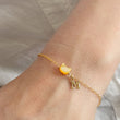 Load image into Gallery viewer, Gold bracelet with a yellow charm and letter 'M' on a wrist against a light background
