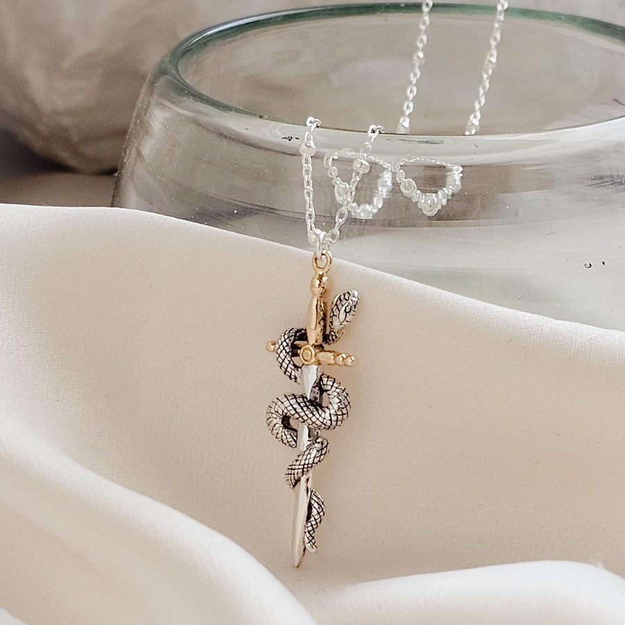 Close-up of the Snake & Dagger Necklace on cream fabric