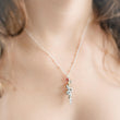 Load image into Gallery viewer, The Snake &amp; Dagger Necklace worn on a model’s neck with a red birthstone accent charm, showing how the pendant hangs delicately from a fine silver chain for a striking yet elegant look.
