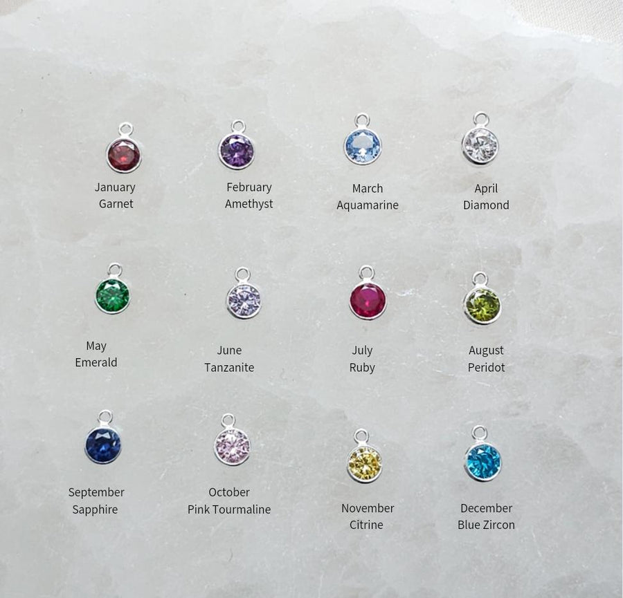 Studio Blue’s 12 gemstone options for customizing the Snake & Dagger Necklace: Garnet (January), Amethyst (February), Aquamarine (March), Clear Quartz (April), Emerald (May), Moonstone (June), Ruby (July), Peridot (August), Sapphire (September), Pink Tourmaline (October), Citrine (November), and Blue Topaz (December). Each gemstone adds a personal touch to this handcrafted pendant.