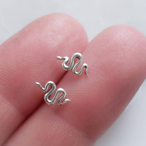 Teeny tiny Snake Studs in Bronze and Sterling silver between 2 fingers by Studio Blue on Etsy