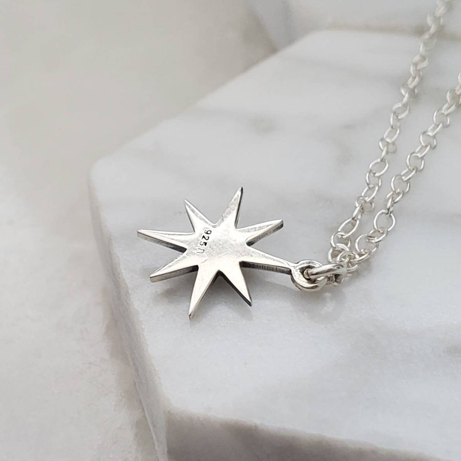 Back side of North Star, Starburst pendant in sterling silver showing .925 hallmark stamp on cable chain, on white background. By Studio Blue on Etsy