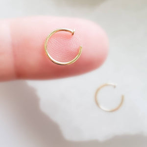 14K Yellow gold Nose Hoop, available in yellow or white gold 20g or 18g on fingertip with white background