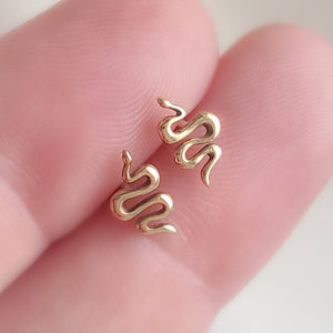 Teeny tiny Snake Studs in Bronze and Sterling silver between 2 fingers. Between 2 fingers by Studio Blue on Etsy