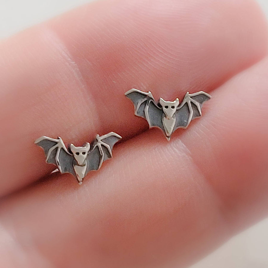 Sterling silver little bat studs between 2 fingers, by Studio Blue on Etsy