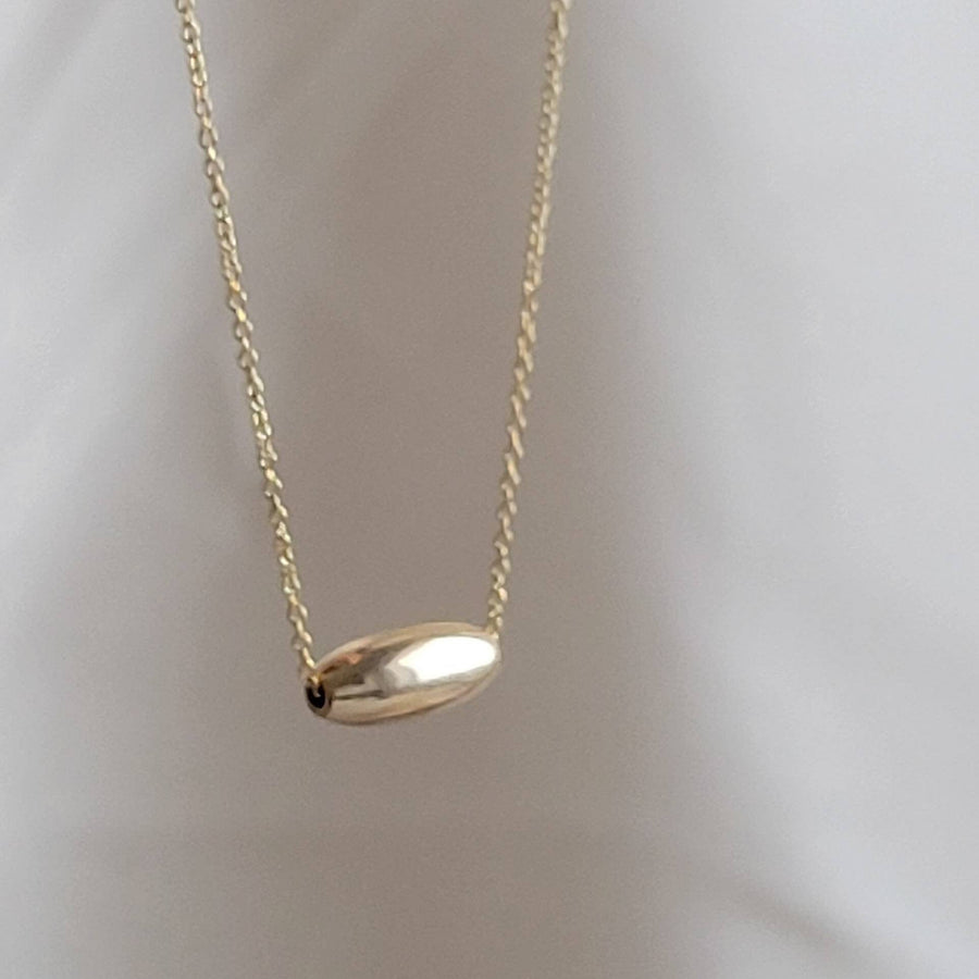 Gold fill oval bead floating on a dainty chain, on a light background, by Studio Blue on Etsy