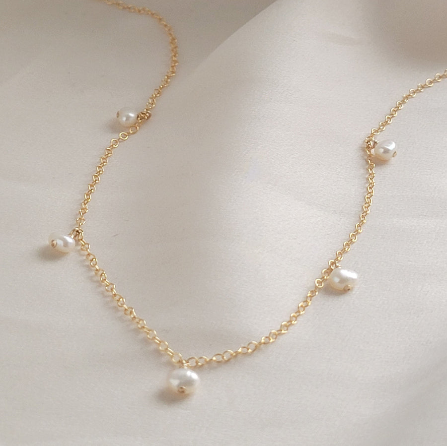 White Keshi pearl drops on delicate 14k gold fill chain, shown on a beige background, by Studio Blue on Etsy