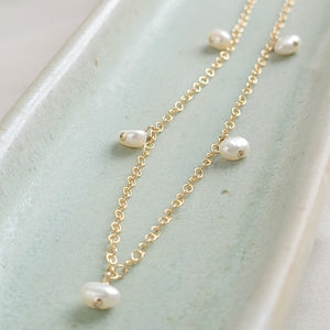 White Baroque pearl drops on delicate 14k gold fill chain, shown on a light green background, by Studio Blue on Etsy