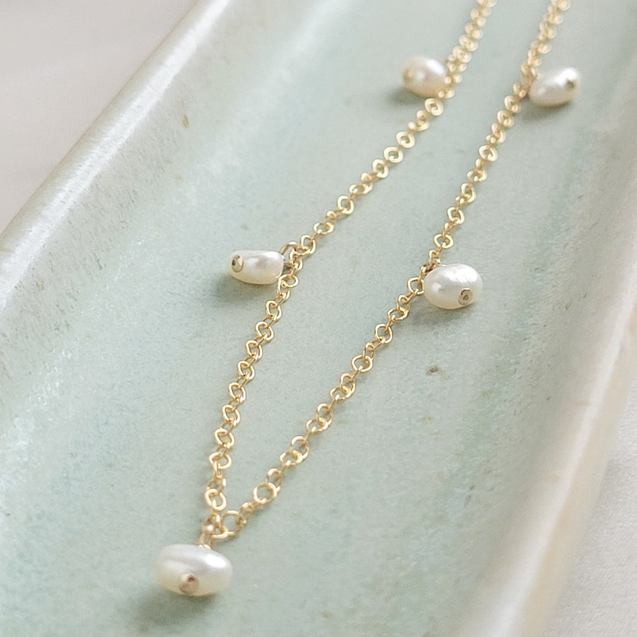 White Baroque pearl drops on delicate 14k gold fill chain, shown on a light green background, by Studio Blue on Etsy