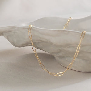 Dainty paperclip link chain necklace in 14k gold fill, shown on shell bowl. By Studio Blue on Etsy