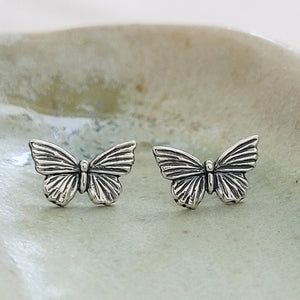 Pair of Sterling silver Butterfly studs earrings shown on sage green background by Studio Blue on Etsy