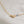 Load image into Gallery viewer, 14k Gold lobster clasp on cable chain finished with a blue bead on beige background by Studio Blue on Etsy
