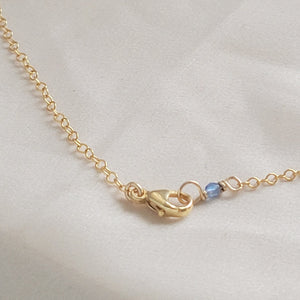 14k Gold lobster clasp on cable chain finished with a blue bead on beige background by Studio Blue on Etsy