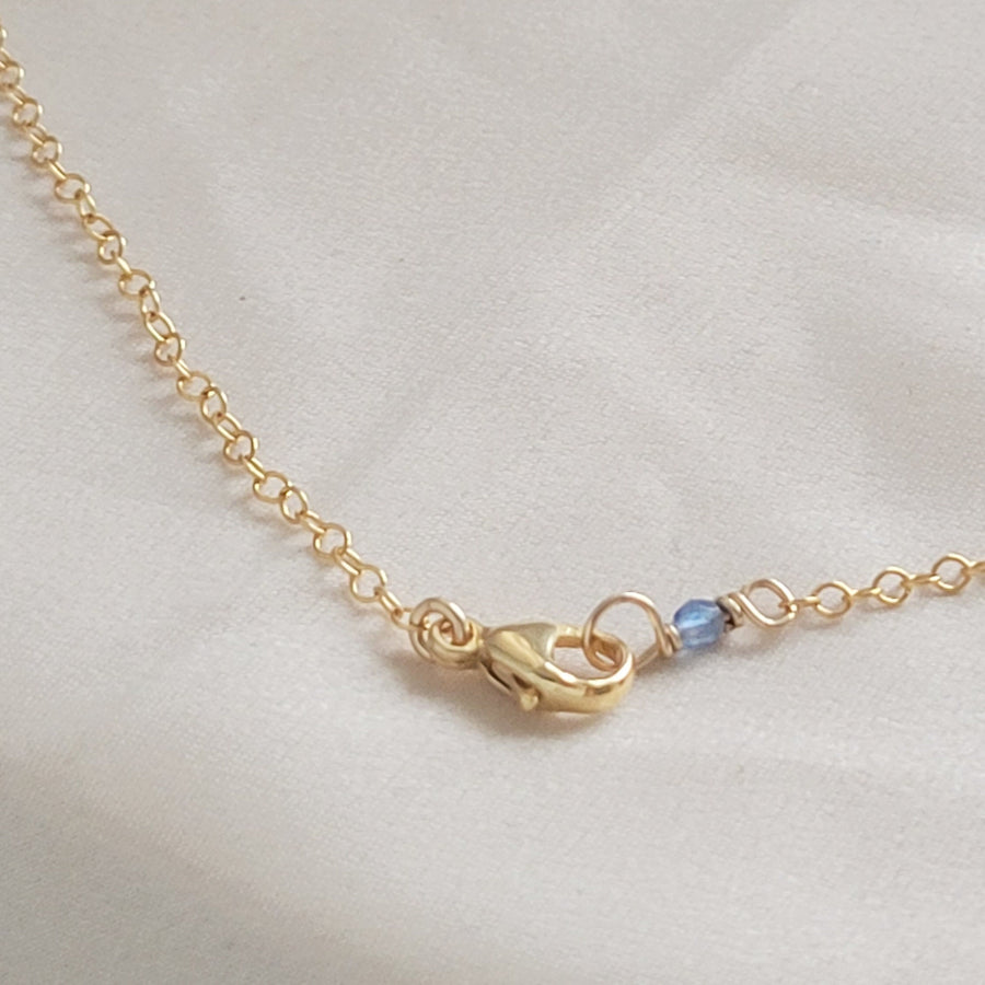 14k Gold lobster clasp on cable chain finished with a blue bead on beige background by Studio Blue on Etsy