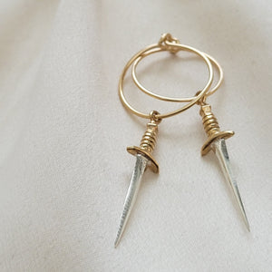 Bronze & Sterling Silver Dagger charm on a 15mm Gold fill hoop earring, shown on a cream color background. By Studio Blue on Etsy