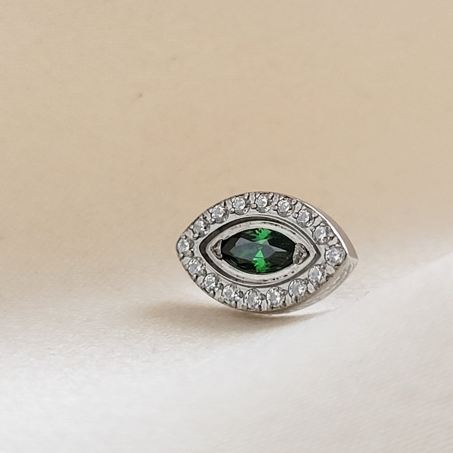 Titanium Evil Eye earring stud with pavé set clear CZ&#39;s around a green, marquise shaped CZ in the center on a cream background byStudio Blue on Etsy